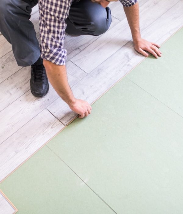 Young worker laying a floor with bright laminated flooring boards