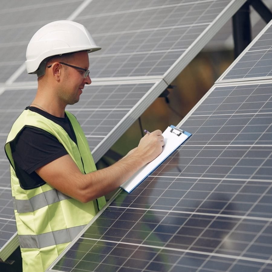 Engineer in a white helmet. Man near solar panel. Worker with a folder.